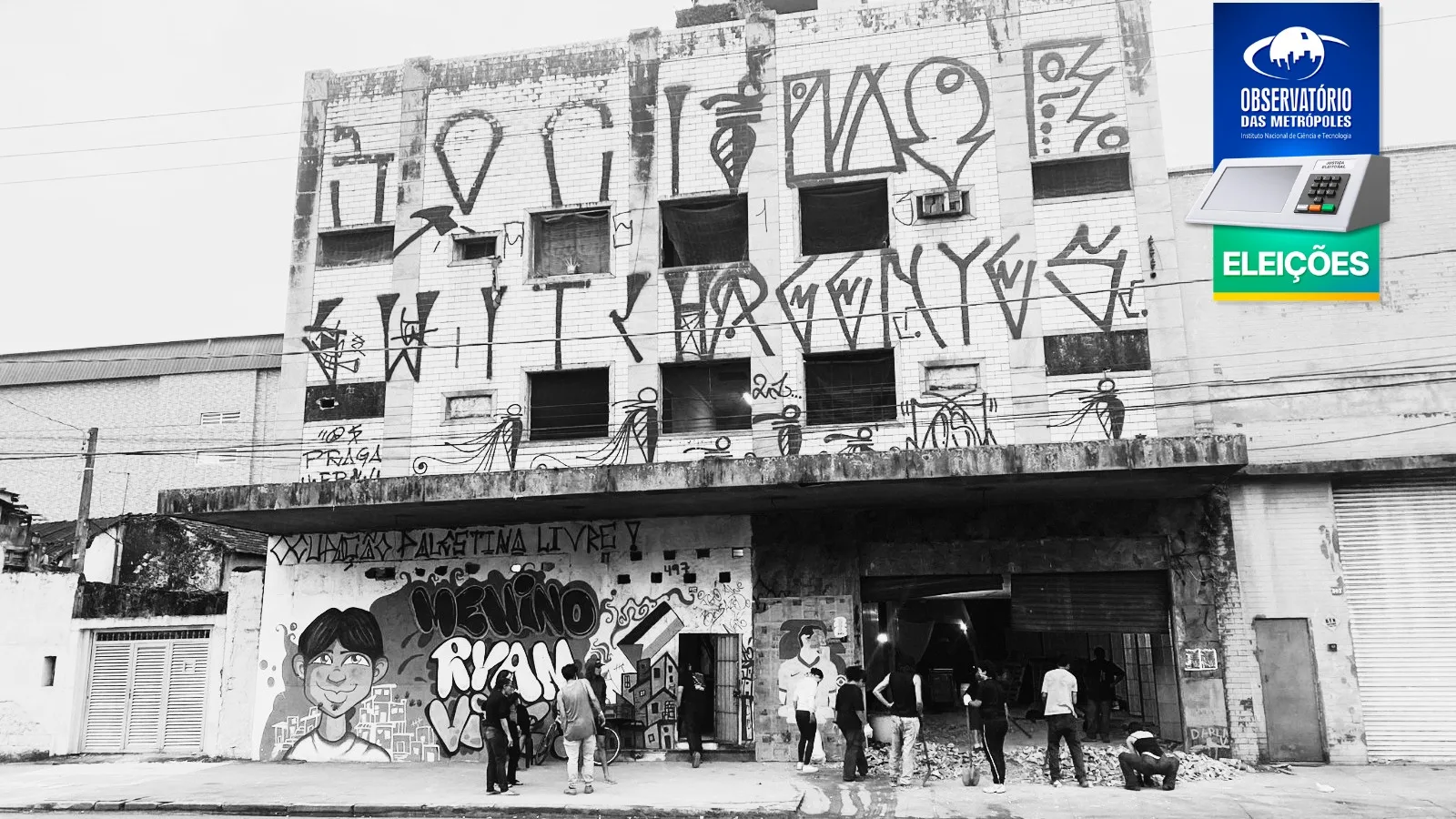 Fotografia em preto e branco de um prédio de três andares, cheio de pichações. Na entrada, um grafite apresenta o nome da ocupação: "Palestina Livre - Menino Ryan Vive".