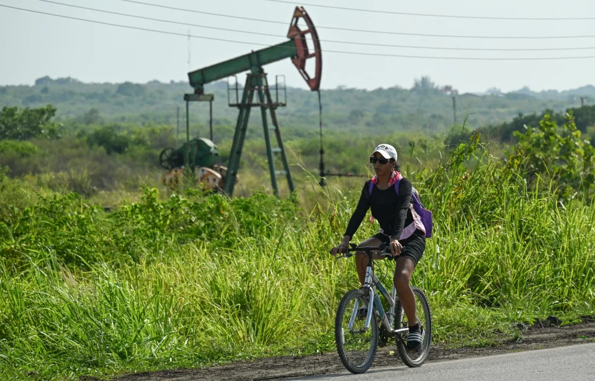 Uma mulher passa de bicicleta por uma antiga bomba de petróleo em Boca de Jaruco, na província de Mayabeque, Cuba, em 29 de julho de 2026.