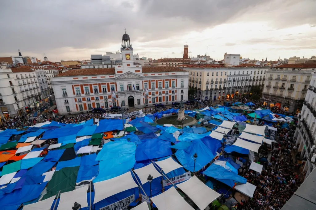 Lonas e tendas cobrem a praça Puerta del Sol enquanto manifestantes mantêm seu acampamento de protesto