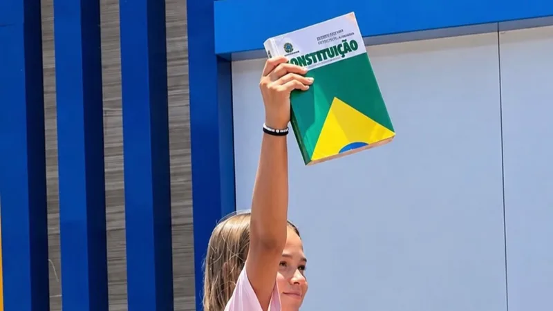 Menina segurando um exemplar da Constituição Federal durante caminhada de apoiadores do presidente Lula (PT)