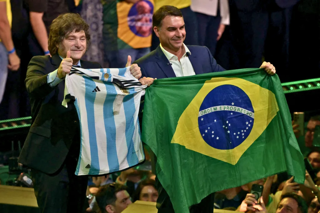 Javier Milei segura o uniforme da seleção argentina ao lado do ultradireitista Flávio Bolsonaro.