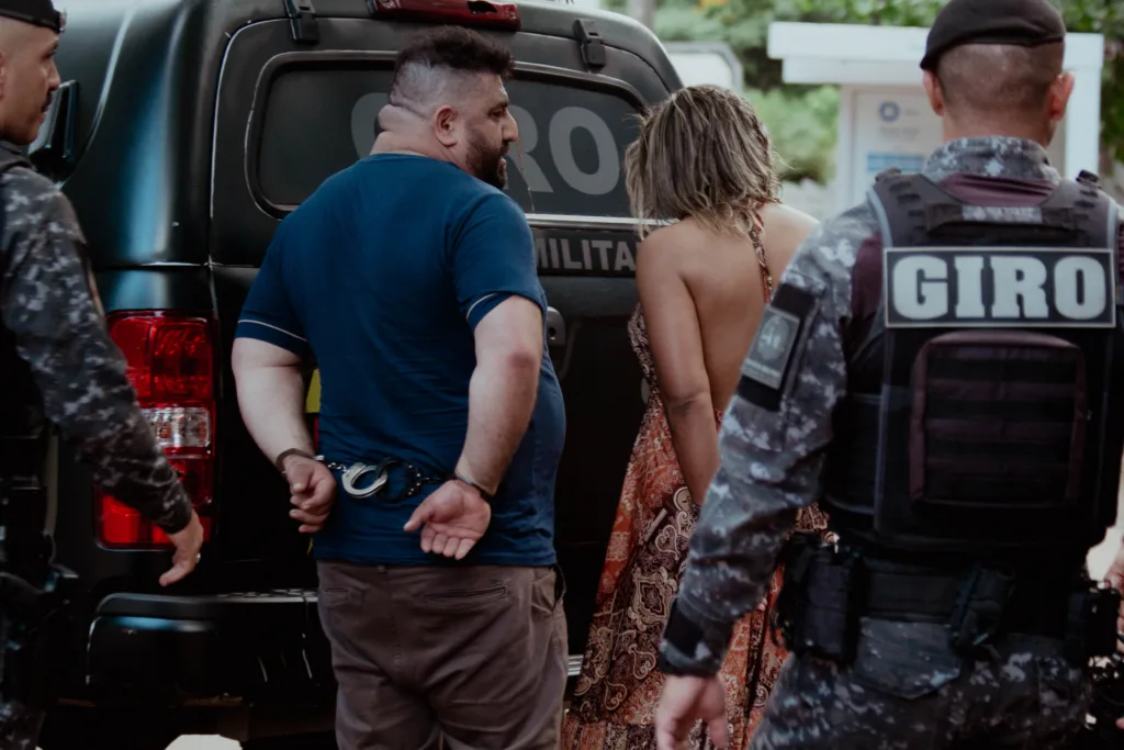 Casal é conduzido por policiais do Giro até a viatura; segundo a Polícia Civil, eles foram levados à Central de Flagrantes por desobediência