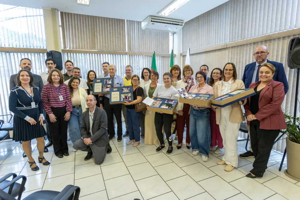 Participantes da cerimônia de entrega posam com os álbuns de fotografias restauradas, na Vara do Trabalho de Encantado