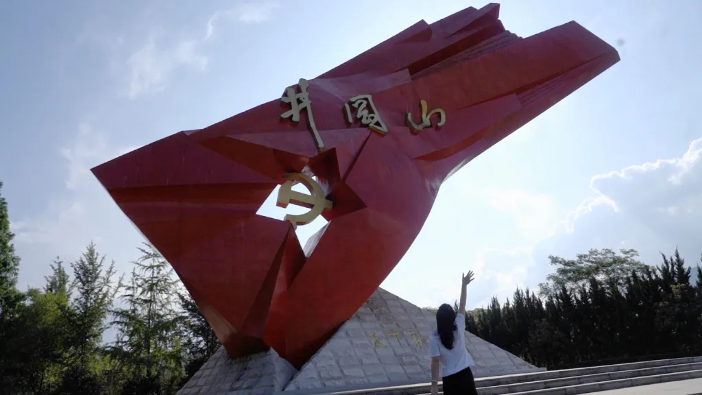 Turista tira foto no monumento "Bandeira Vermelha de Jinggang", localizado em Jingganshan, na província de Jiangxi. O lugar não faz parte da rota da Longa Marcha, mas foi a primeira base revolucionária rural, estabelecida por Mao Zedong em 1927. 24 de maio de 2024