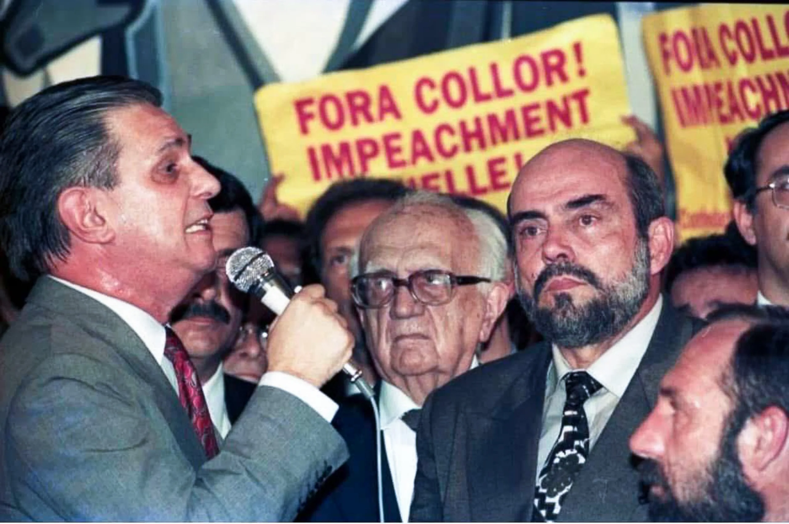 Fotografia de Collor discursando. Ao fundo, vemos faixas pedindo seu impeachment