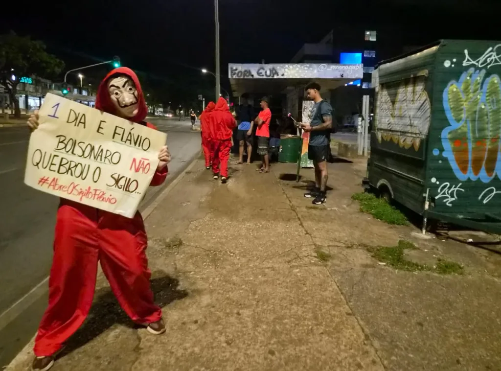 Voluntários fantasiados distribuem materiais e exibem cartaz que cobra de Flávio Bolsonaro a abertura de sigilo, durante ação de mobilização na W3 Norte, em Brasília