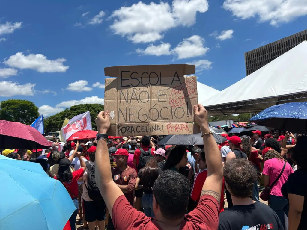 Manifestantes levantam cartaz durante ato de professores da rede pública do DF contra medidas do governo de Celina Leão e em defesa da autonomia das escolas